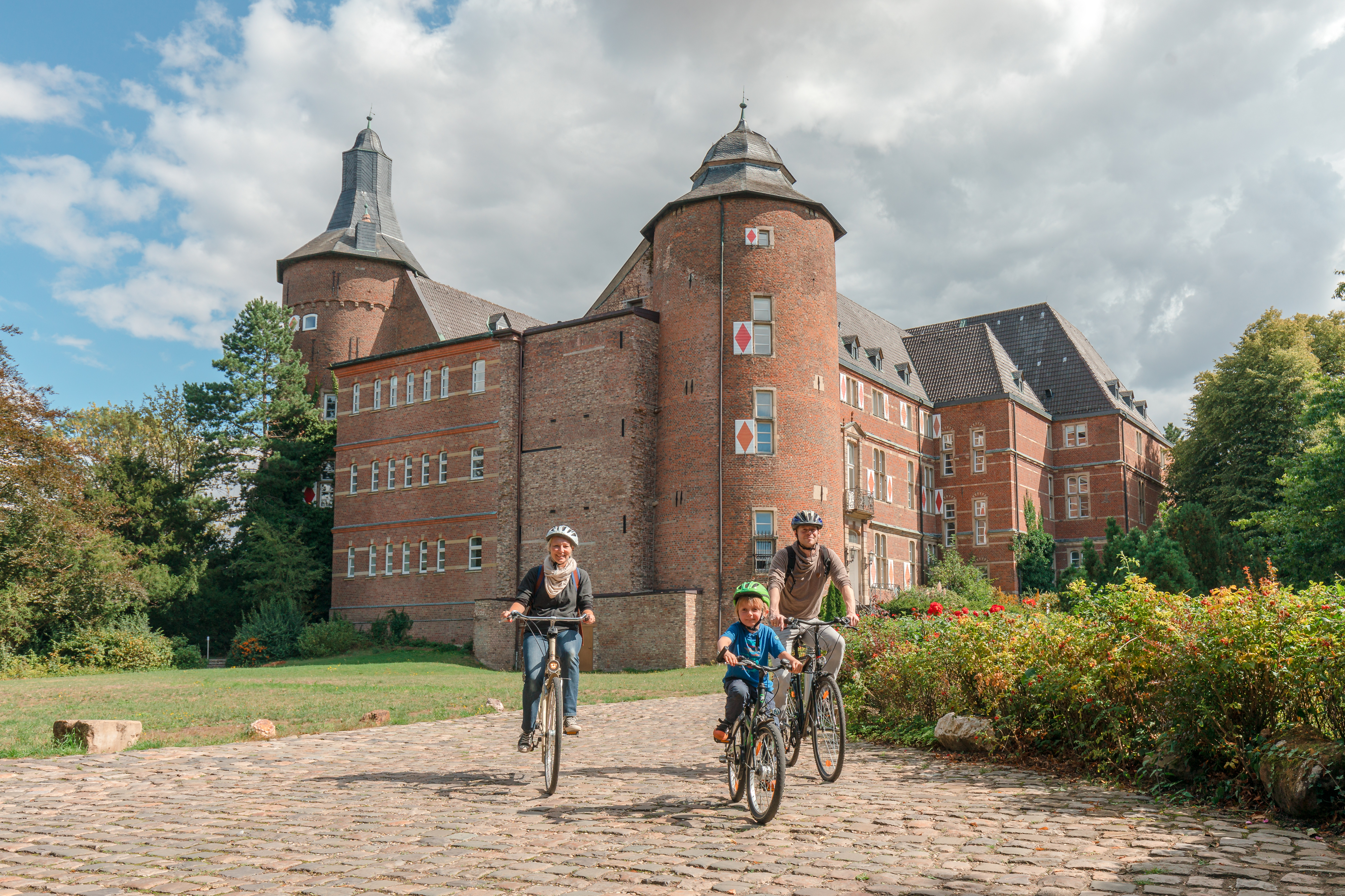 Radfahrer am Schloss Bedburg, einer von vielen Wasserburgen in der Radregion Rheinland